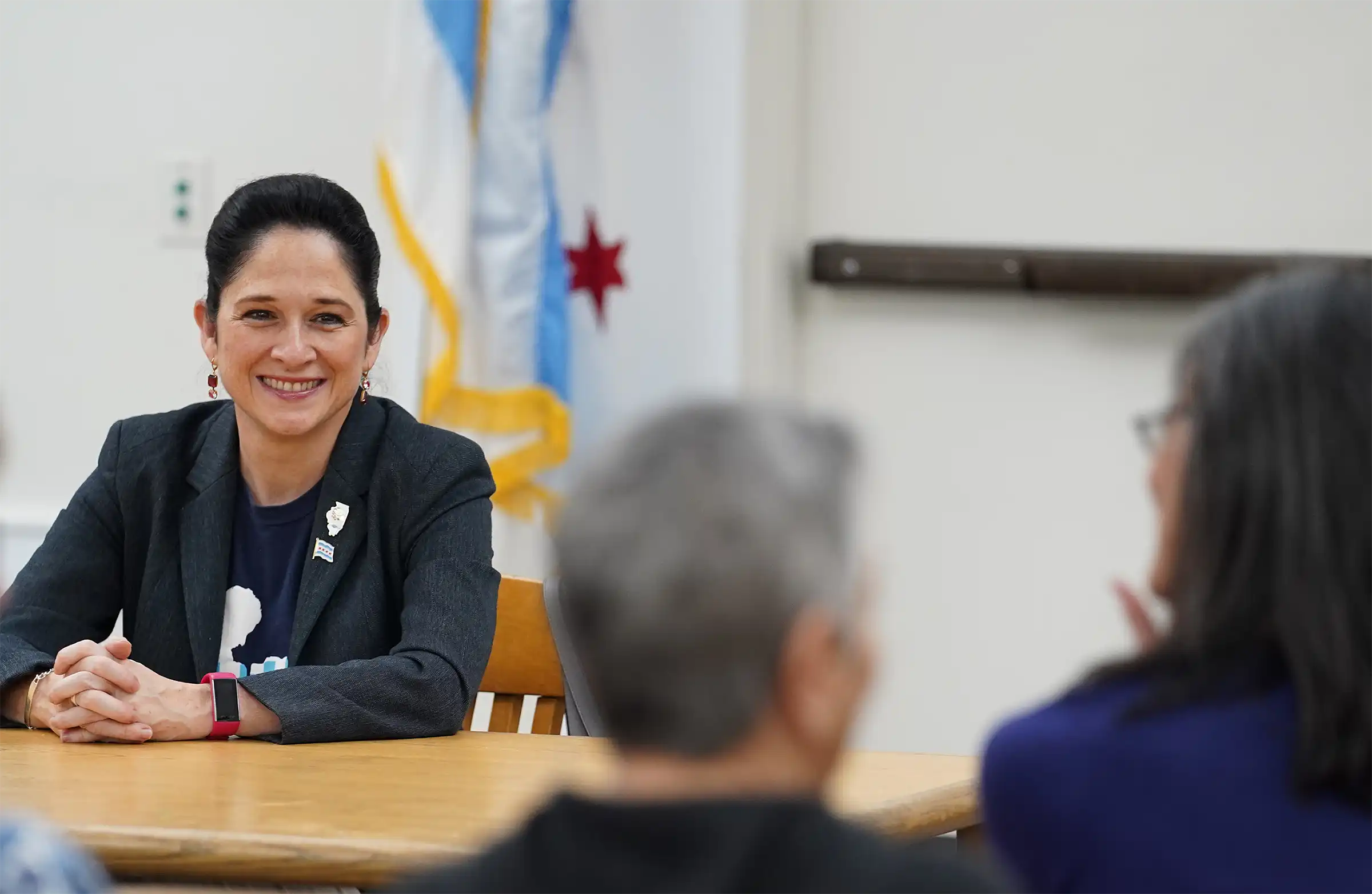 Susana Mendoza sitting at a table with a smile listening to constituents 