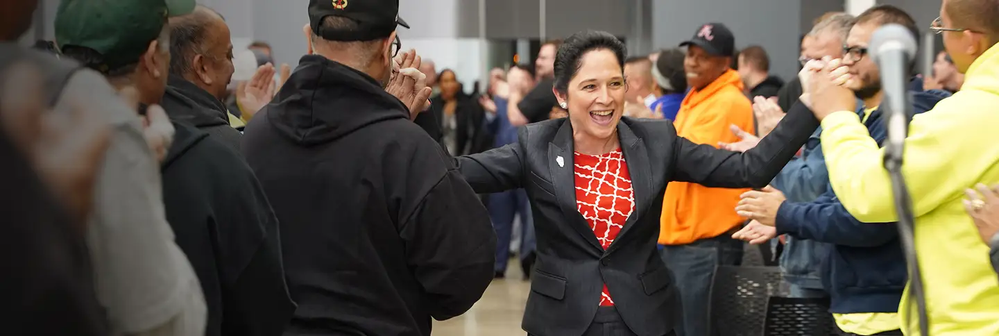 photo of Susana Mendoza shaking and slapping hand as she walks past some constituents in a crowd